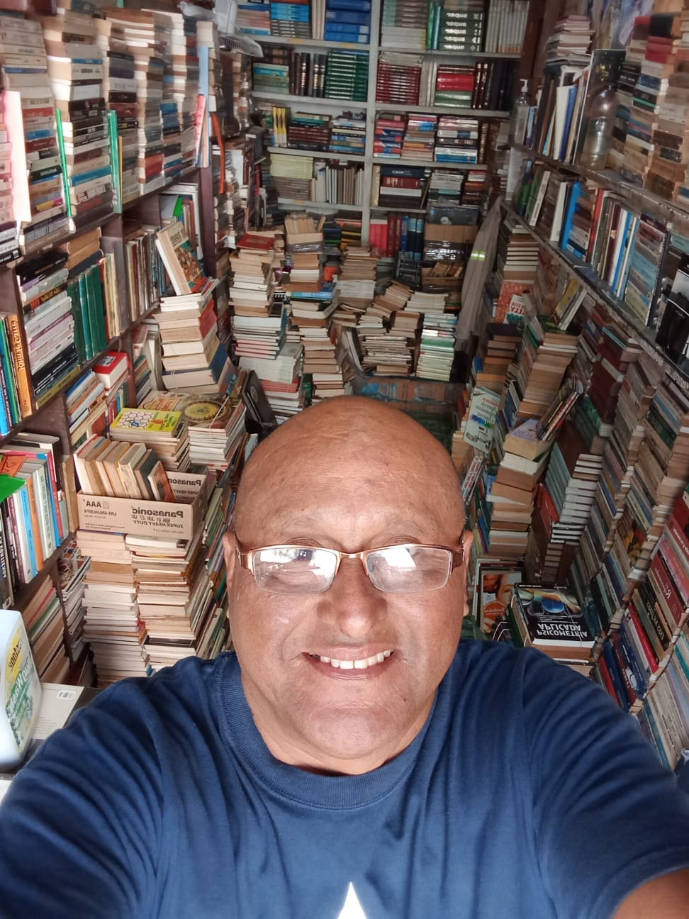 Persona sonriente rodeada de una gran cantidad de libros